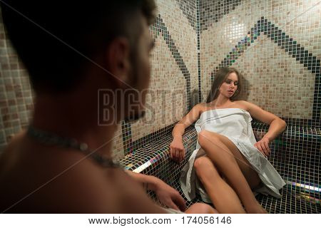 Gorgeous longhaired young blonde wrapped in white towel posing in hamam his young sexy lover looking at her