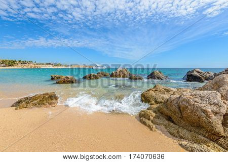 Fantastic sky, ocean and rocks. Differen stages of the waves on the ocean sand. Playa El Chileno Beach, Cabo San Lucas, Mexico.