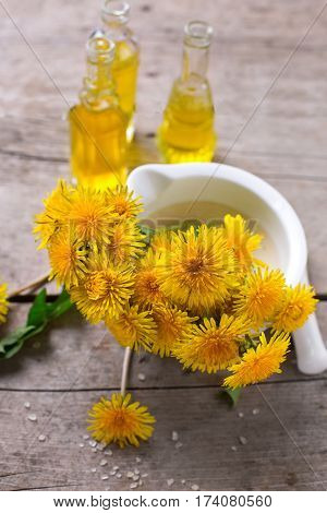 Fresh yellow flowers tussilago in mortar on wooden background. Wellness setting. Selective focus.