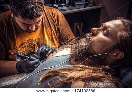 Professional tattoo artist makes tattoo in studio./Tattoo specialist posing in salon.