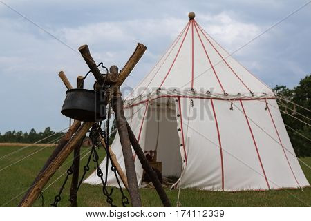 White Tent and Wooden Tripod for Bonfire on Meadow