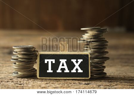 strack of coins with tax wording on wooden tag for business and financial concept
