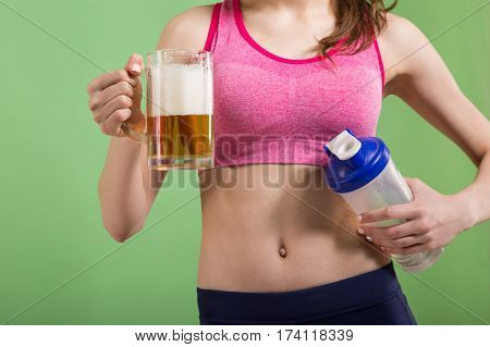 Caucasian girl that chooses between mug of beer or protein shake bottle. Choice concept.