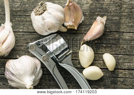 Garlic and garlic press on old wooden table. Top view.