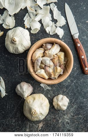 Fresh garlic in wooden bowl with knife. Top view.