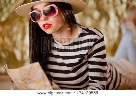 Woman traveler wearing hat holds city map
