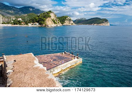 PETROVAC, MONTENEGRO - SEPTEMBER 20, 2016:Tourists stand on the pier in the bay of Petrovac, Montenegro.