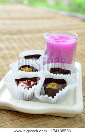 Closeup chocolate sweets in paper pumpkins with pink candle