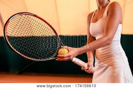 Sportswoman at the tennis court with racquet. Indoor tennis court