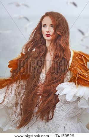 beautiful girl with red hair walking along the seashore. winter photos