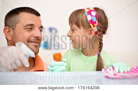 happy father with his small daughter cleaning table together at home