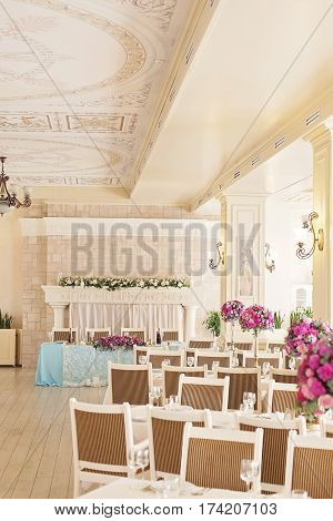Celebrations hall, elegant banquet hall interior. Tables set for meal. Bright and colors checkered ceiling in colorful modern interior with chandelier. Elements of the decor
