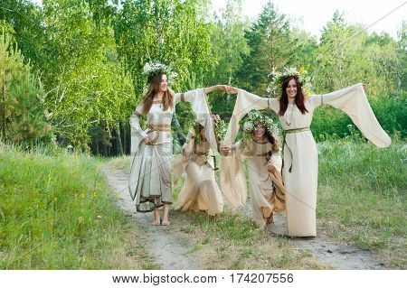 Attractive Women with Wreath of Flowers play game streamlet in forest. Ivan Kupala Holiday Celebration