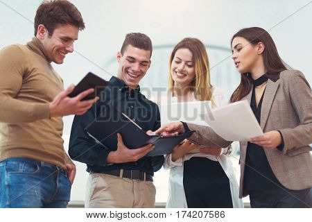 Group of people standing close to each other while and gesturing. Group of students preparing for exams discuss in the hall.