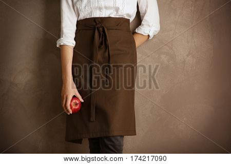 Woman wearing apron on color background