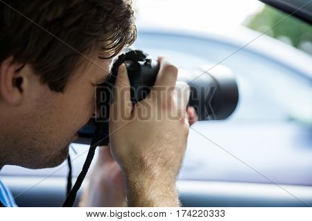Private Detective Sitting Inside Car Photographing With SLR Camera