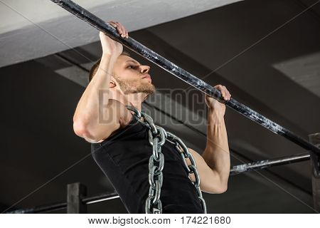 Athlete Man Wearing A Metal Chain Doing Pull-ups On Horizontal Bar In The Gym