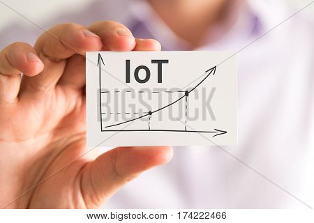 Businessman Holding A Card With Iot Internet Of Things Rising Arrow And Chart