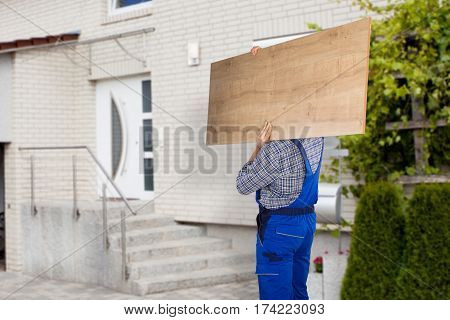 Mover Carrying Piece Of Furniture To The House