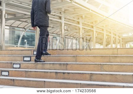 Business man with smartphone walking up stairs to office.