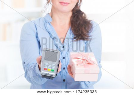 Woman seller gives payment terminal and goods to the client to pay for