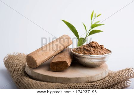 Ayurvedic Chandan powder or sandalwood paste in silver bowl with sticks and leaves placed over sahan or sahana or circular stone base for creating paste