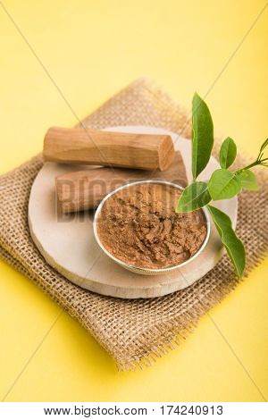 Ayurvedic Chandan powder or sandalwood paste in silver bowl with sticks and leaves placed over sahan or sahana or circular stone base for creating paste