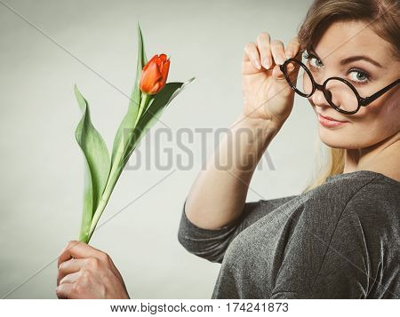 Leisure feelings flora nature beauty feminine concept. Seducive nerdy girl holding tulip. Young blonde lady with red flower.