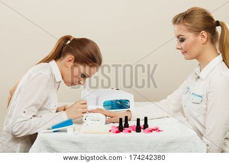 Relaxing time and wellness day concept. Blonde elegant woman visiting professional manicurist salon. Beautician makes perfect nails to client.