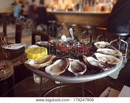 Oysters on ice plate served with lemon and sauce in the oyster bar.