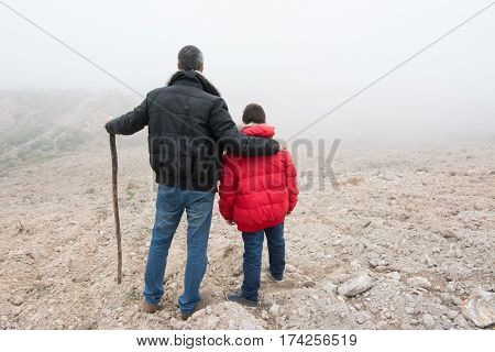 Concept of family escaping. Father and son in a mountain road with fog. Scene with actors