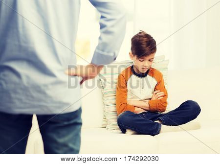 people, misbehavior, family and relations concept - close up of upset or feeling guilty boy and father at home