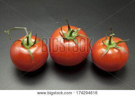 Ripe tomatoes on black background.
