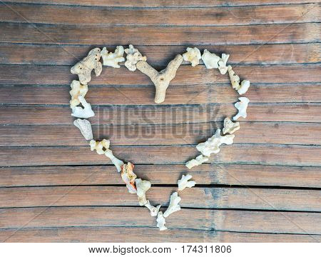 Heart from sea corals on wooden background. Heart symbol for Valentine's Day. Shabby chic romantic decor on rustic wood board. White coral mosaic for love and romance. Seaside holiday banner template