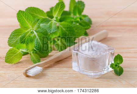 alternative natural toothpaste himalayan salt and wood toothbrush mint on wooden background