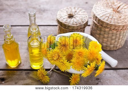 Fresh yellow flowers tussilago in mortar on wooden background. Wellness setting. Selective focus.