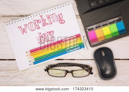 Workspace notebook and inscription in a scratchpad: working day