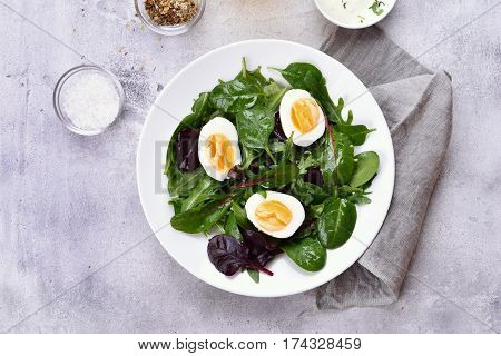 Salad with eggs and green leaves of spinach arugul. Healthy food top view