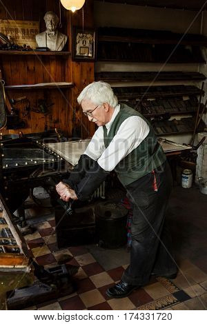 IRONBRIDGE UK - CIRCA 2013: A man in period costume works a traditional printing press at Blists Hill Victorian Museum Shropshire UK