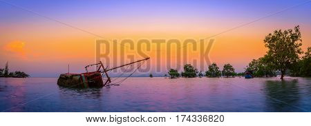 The old fishing boat capsized on sea at sunset in Phuket Thailand.