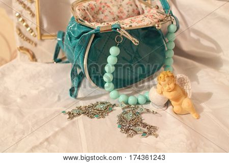 lady's accessories turquoise color purse with beads, silver earrings and little sleep angle beautify for home
