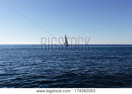 Luxury yacht with white sails sailing in clear blue water of Mediterranean Sea near Cinque Terre, Italy on a sunny day with clear blue sky.