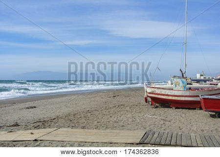CABO DE GATA SPAIN - FEBRUARY 9 2016: Fishing boats at the shore of national park Cabo de Gata near Almeria (Andalusia Spain) and sea waves on the background.