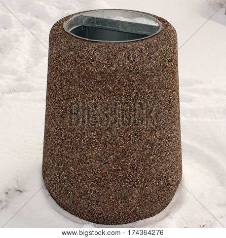 Dustbin of granite in the snow. Urban landscaping.
