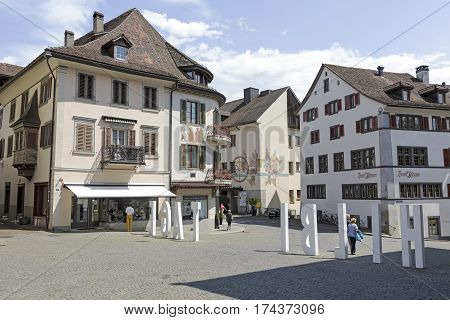 RAPPERSWIL SWITZERLAND - MAY 10 2016: Buildings of the city in the old town. Large white lettering set on the square between the houses and several people can be seen in a distance