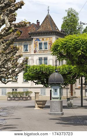 RAPPERSWIL SWITZERLAND - MAY 10 2016: Column that shows the weather data is located on a pavement next to the small fountain. The view is complemented by historic architecture and a lot of greenery