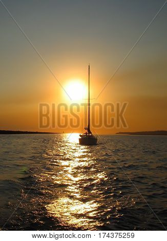 A sailboat in California on the Pacific Ocean, underway at sunset.