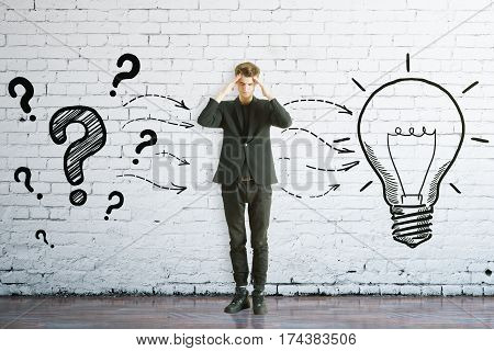 Thoughtful man with drawn question marks and lamp on brick background. Idea concept