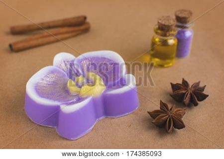 Original handmade soap shaped like orchid. Essential oil cinnamon and anise on the background.