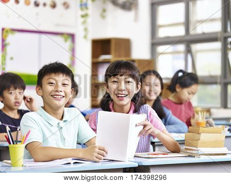 portrait of asian elementary school students in classroom looking at camera smiling.